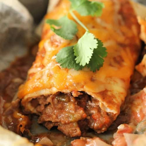 Close-up of a beef burrito with melted cheese and cilantro garnish.