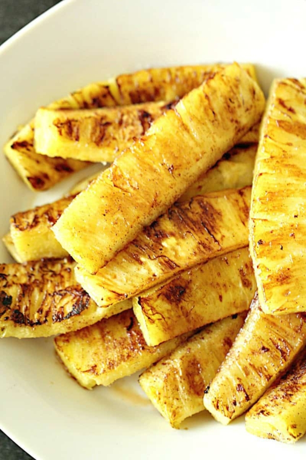 Grilled pineapple slices arranged on a white plate.