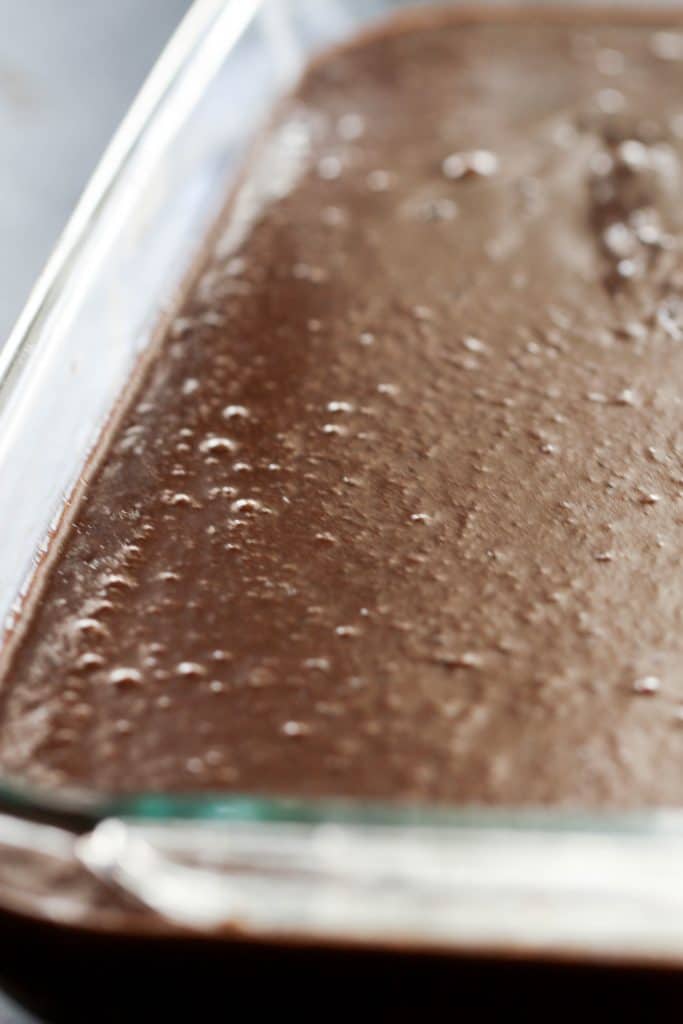 Fudgy Brownies topped with chocolate frosting in baking dish.