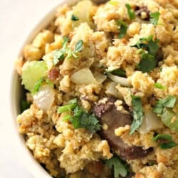A close-up of a bowl filled with cornbread stuffing, featuring chunks of celery, onion, herbs, and pieces of bread.