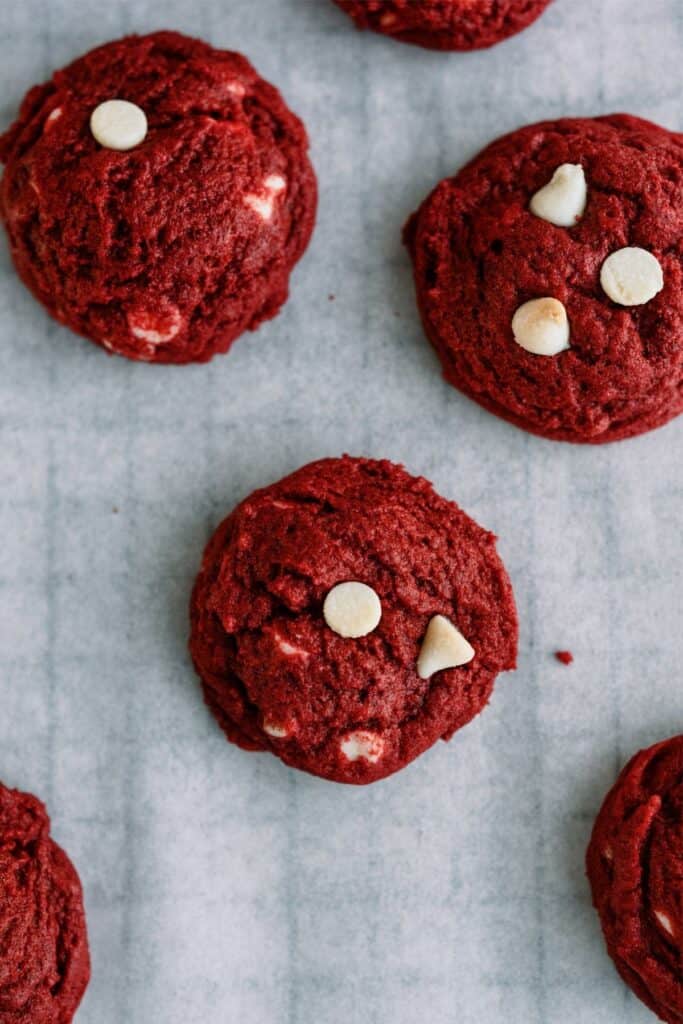 Top view Red Velvet White Chocolate Chip Cookies on a cooling rack lined with parchment paper.