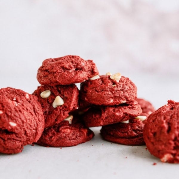 Red Velvet White Chocolate Chip Cookies stacked on a countertop.