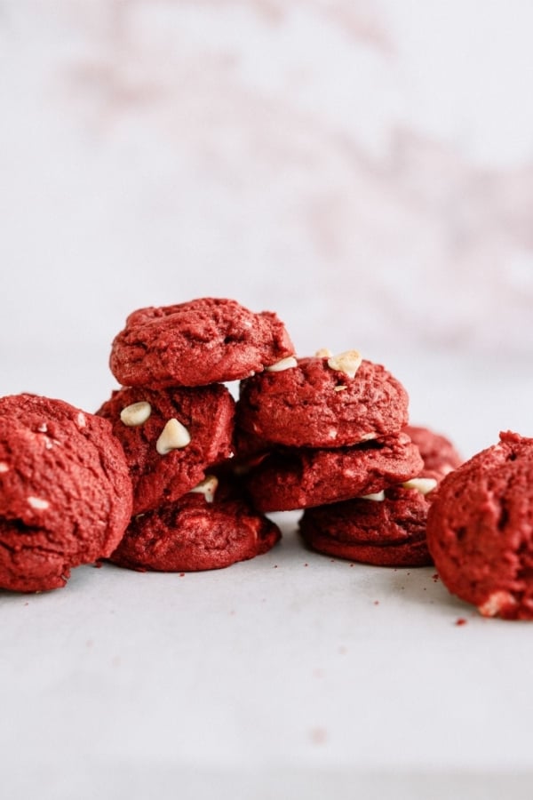 Red Velvet White Chocolate Chip Cookies stacked on a countertop.
