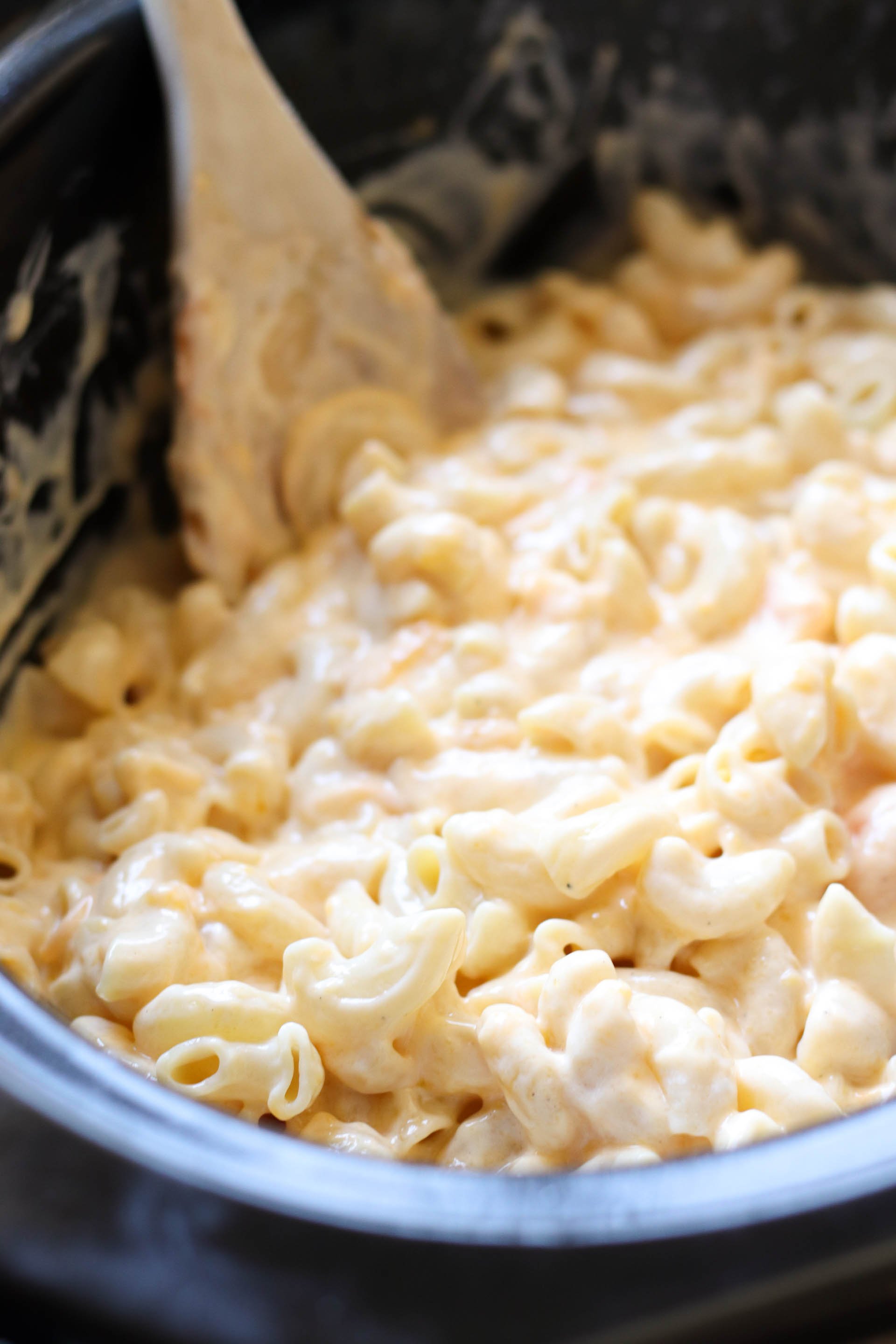 macaroni being mixed with cheese sauce in slow cooker