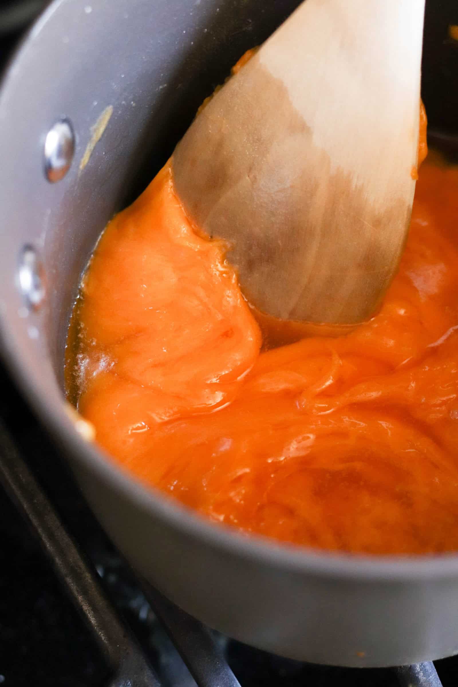 cheese melting in a saucepan and being stirred with a wooden spoon