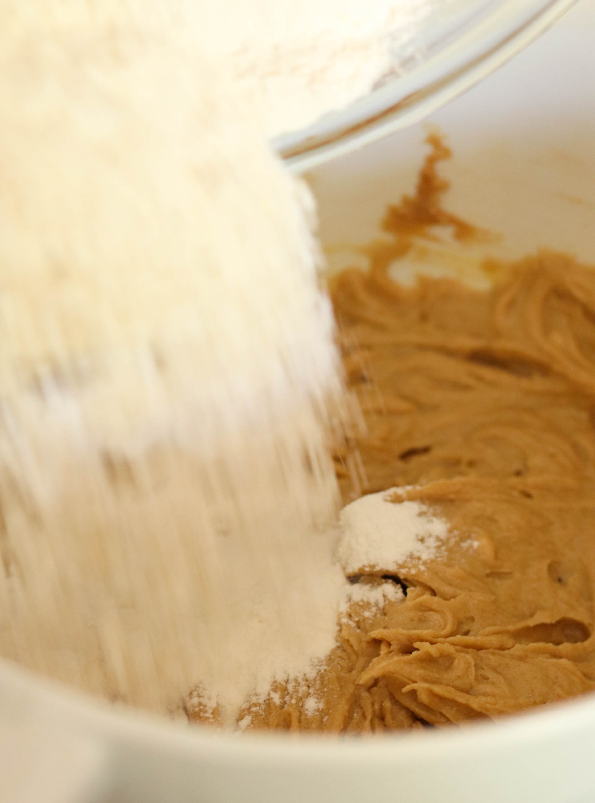 Adding flour to cookie dough in mixing bowl