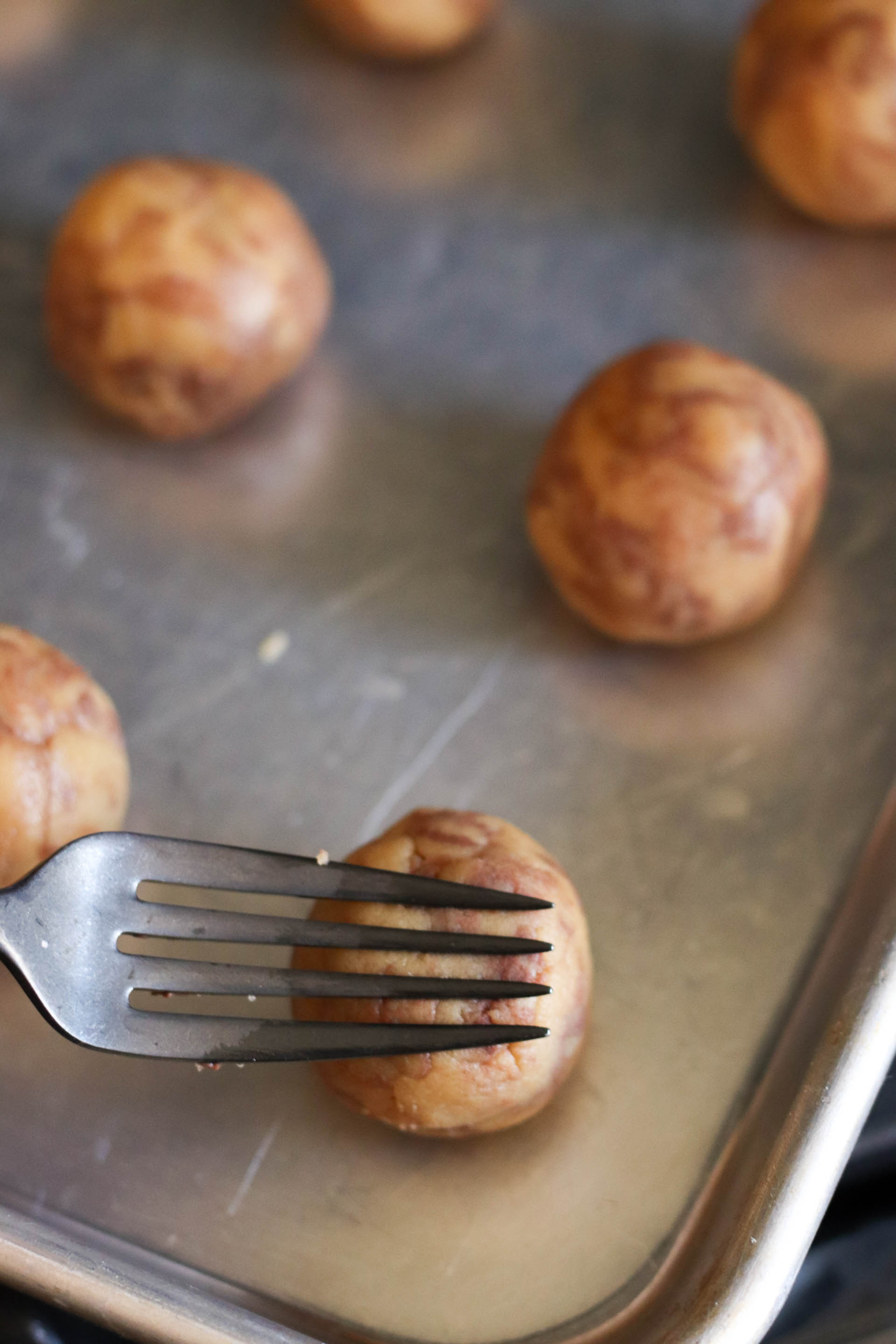 Fork pressing down on a cookie dough ball