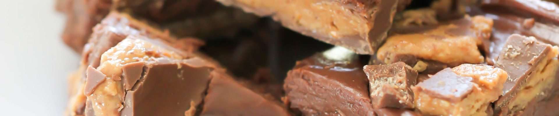 A white plate contains a stack No Bake Reese's Fudge Bars.