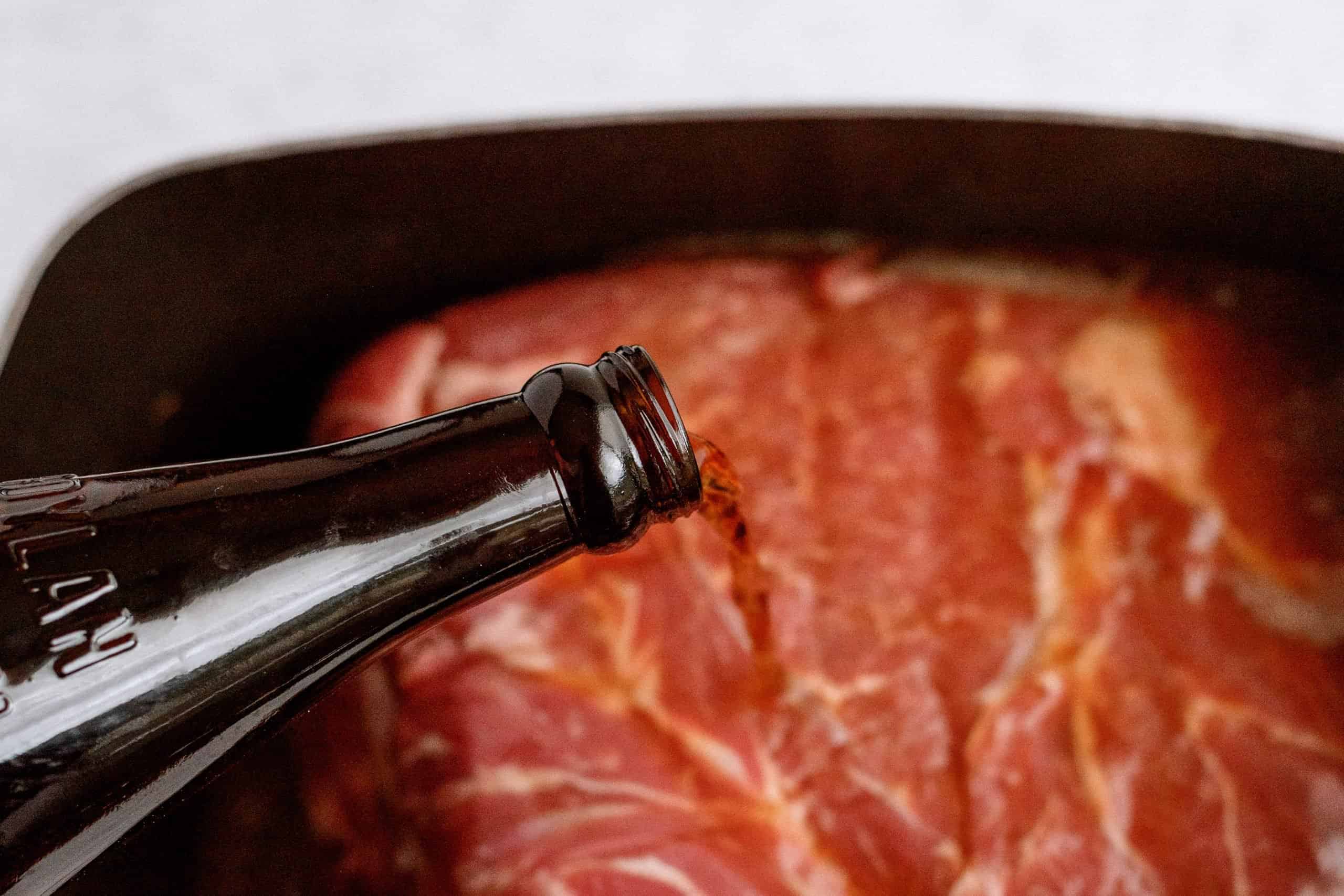 Pouring root beer on top of roast in slow cooker