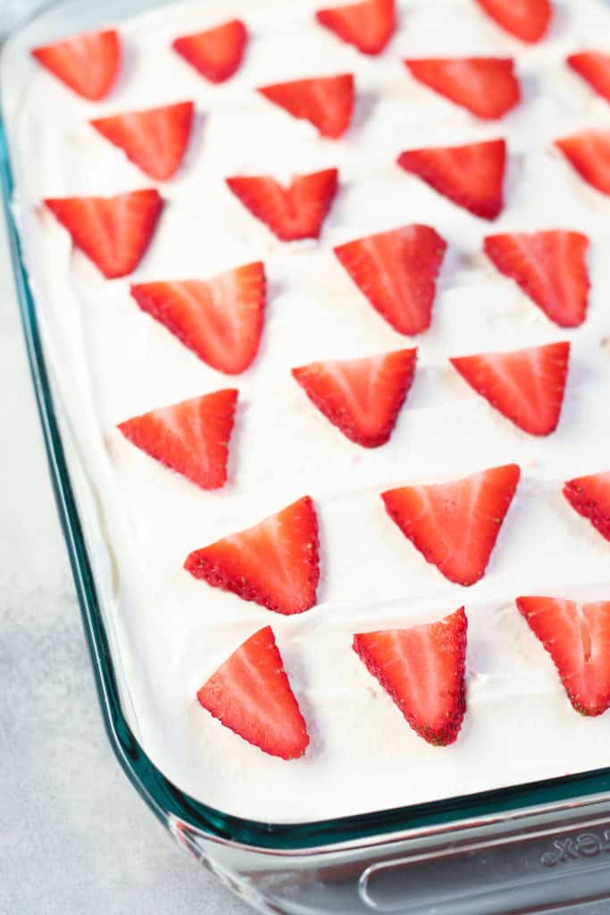 Strawberries and Cream Poke Cake with fresh sliced strawberries on top.