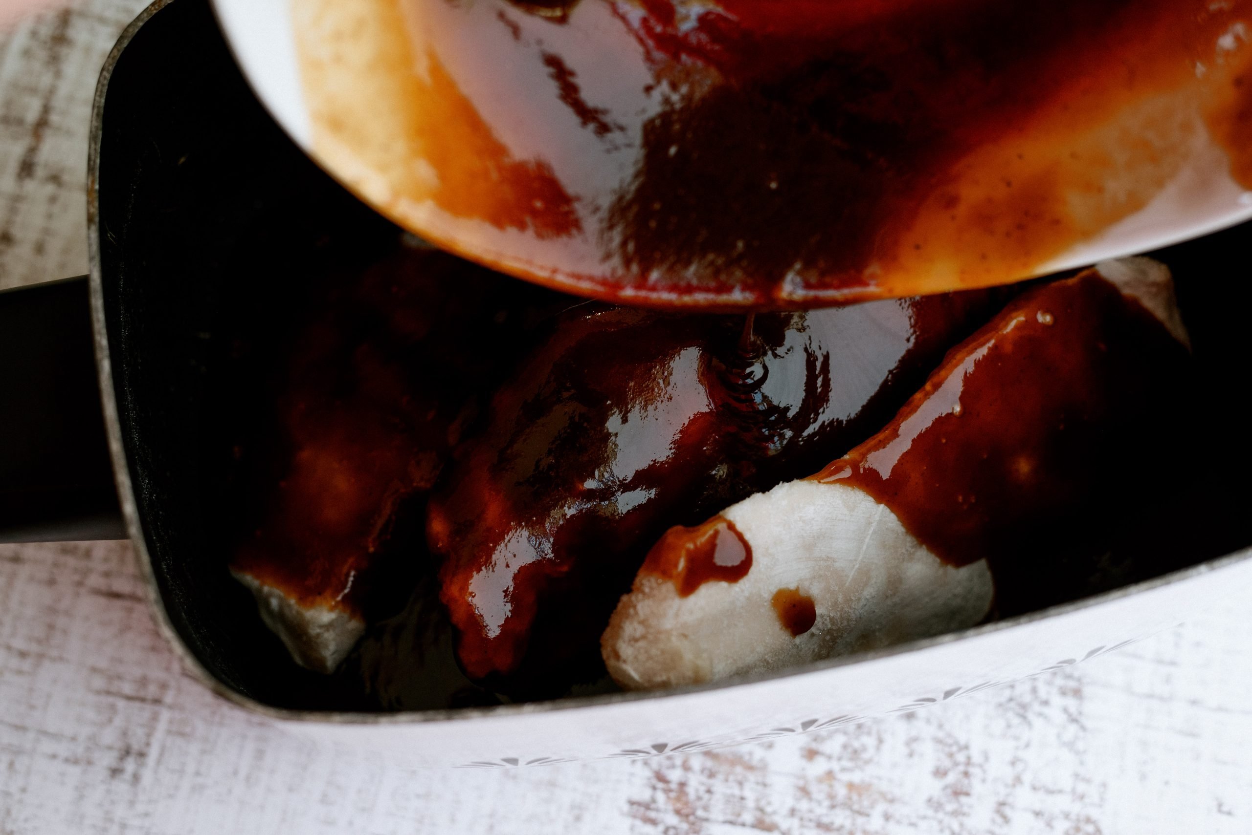 Pouring BBQ Sauce on top of chicken in slow cooker