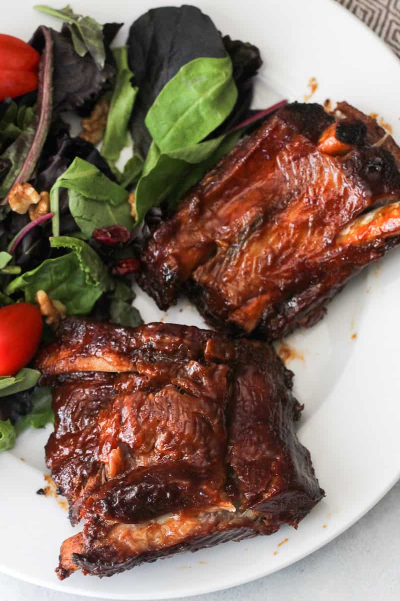 Fall Off The Bone BBQ Ribs on a white plate served with salad