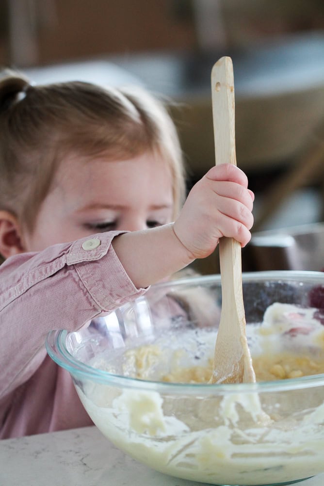 Little girl mixing banana muffin batter with wooden spoon