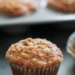 Banana Crumb Muffins with one in front and the remaining muffins in the tin.