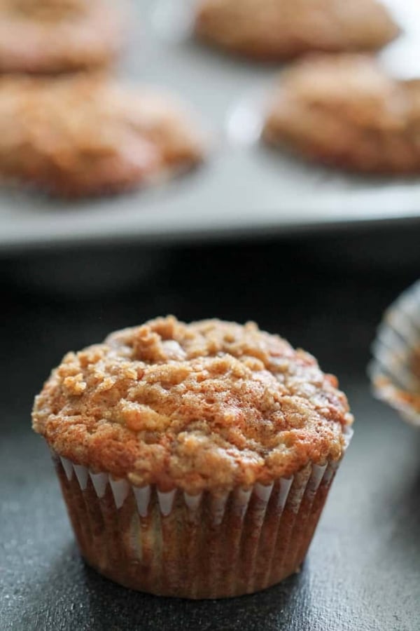 Banana Crumb Muffins with one in front and the remaining muffins in the tin.