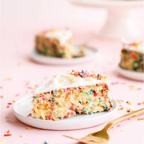 A slice of Funfetti Cake and Buttercream Frosting on a plate with other plates with slices of cake in background,