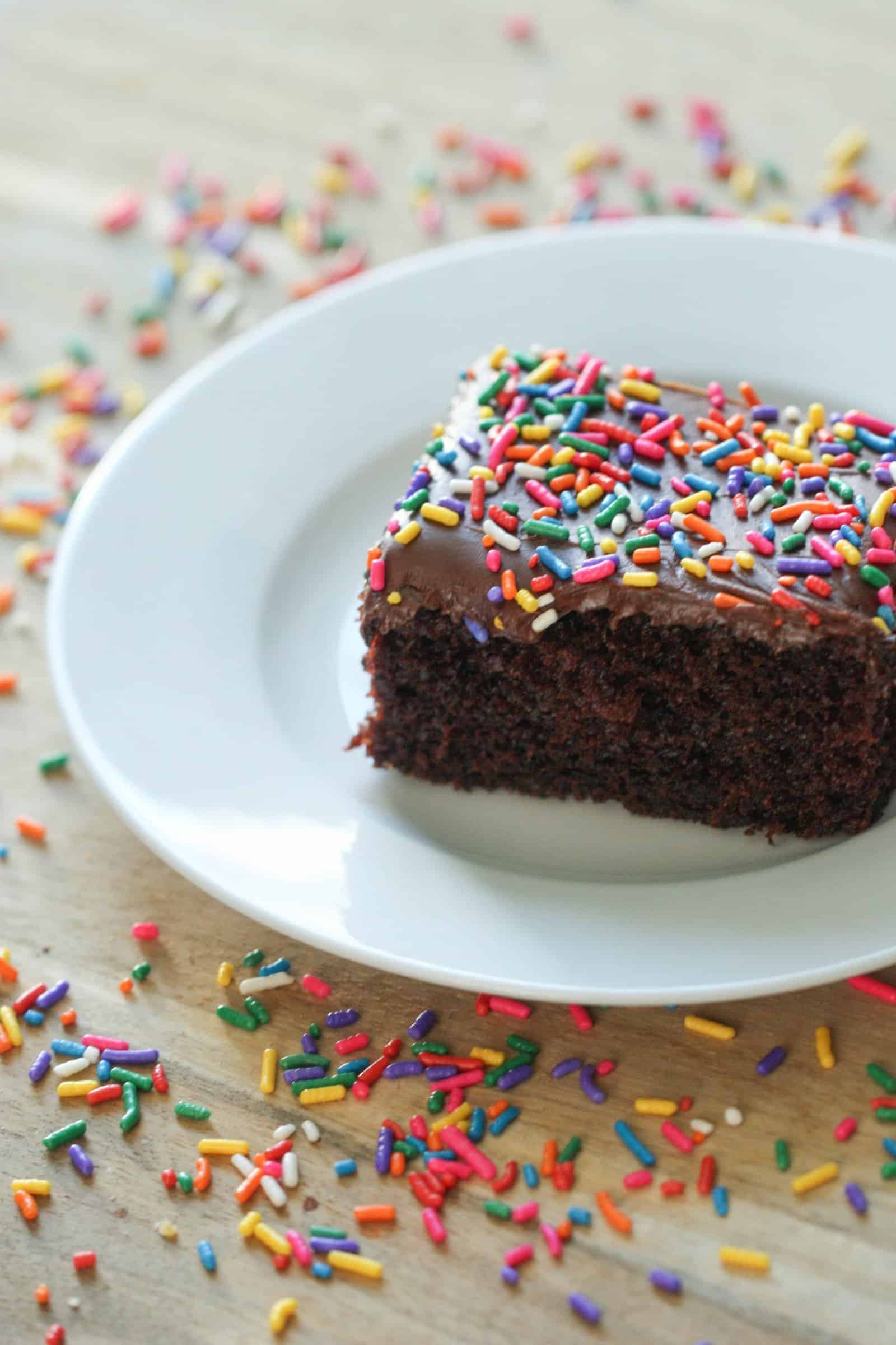 Frosted slice of One Bowl Chocolate Cake (Made from scratch) on a plate topped with sprinkles