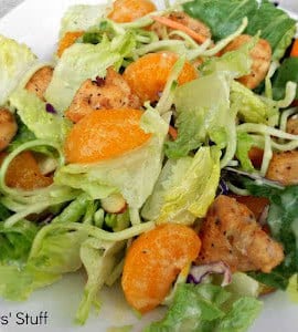 A plate of salad featuring mixed greens, orange segments, and seasoned grilled chicken pieces.