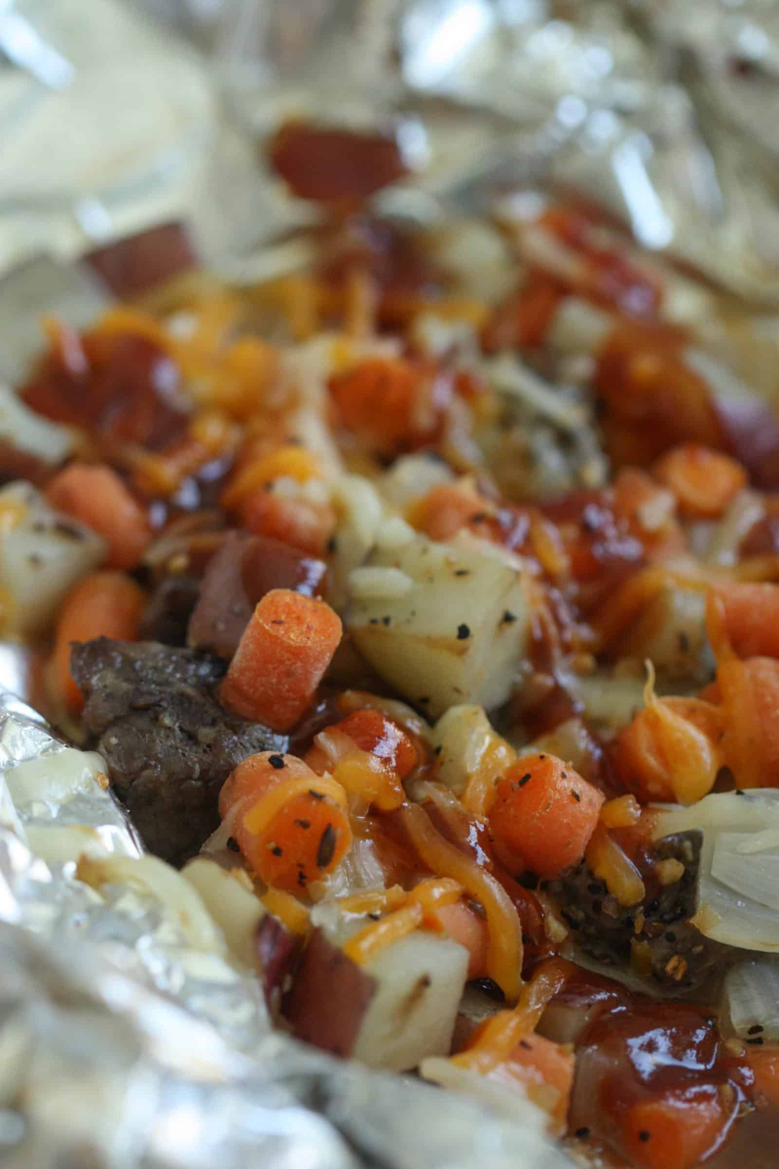 Cooked beef, carrots, potatoes and onions on a piece of foil
