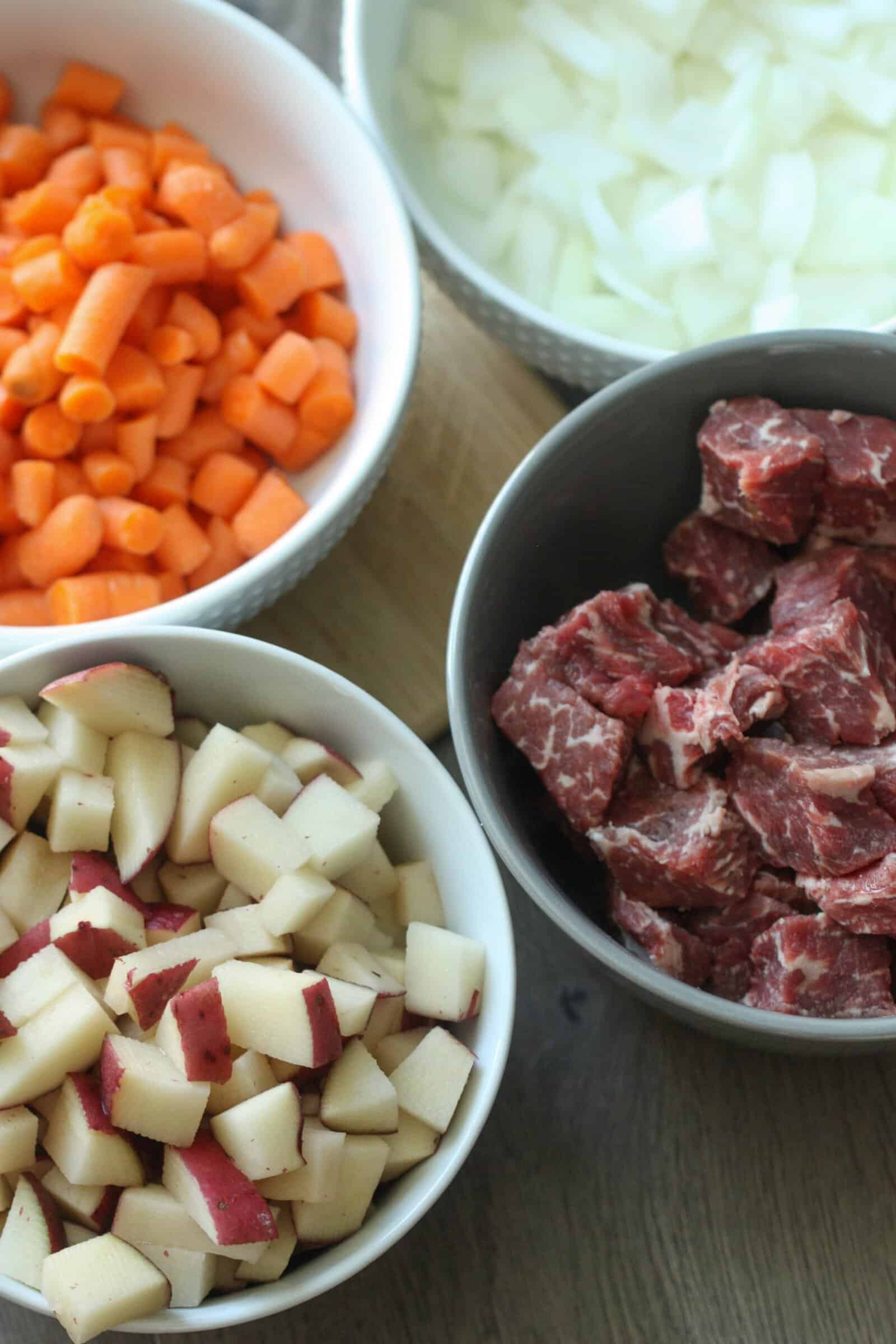 diced meat, carrots, onions and potatoes in bowls