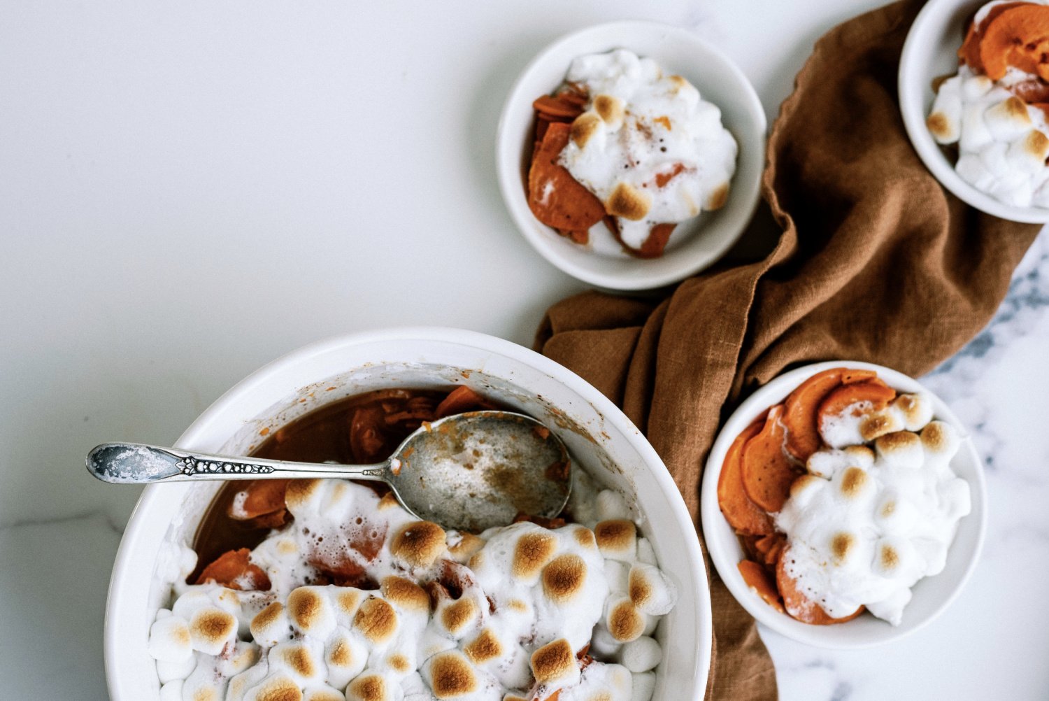sweet potatoes cooked and topped with marshmallows in small white bowls