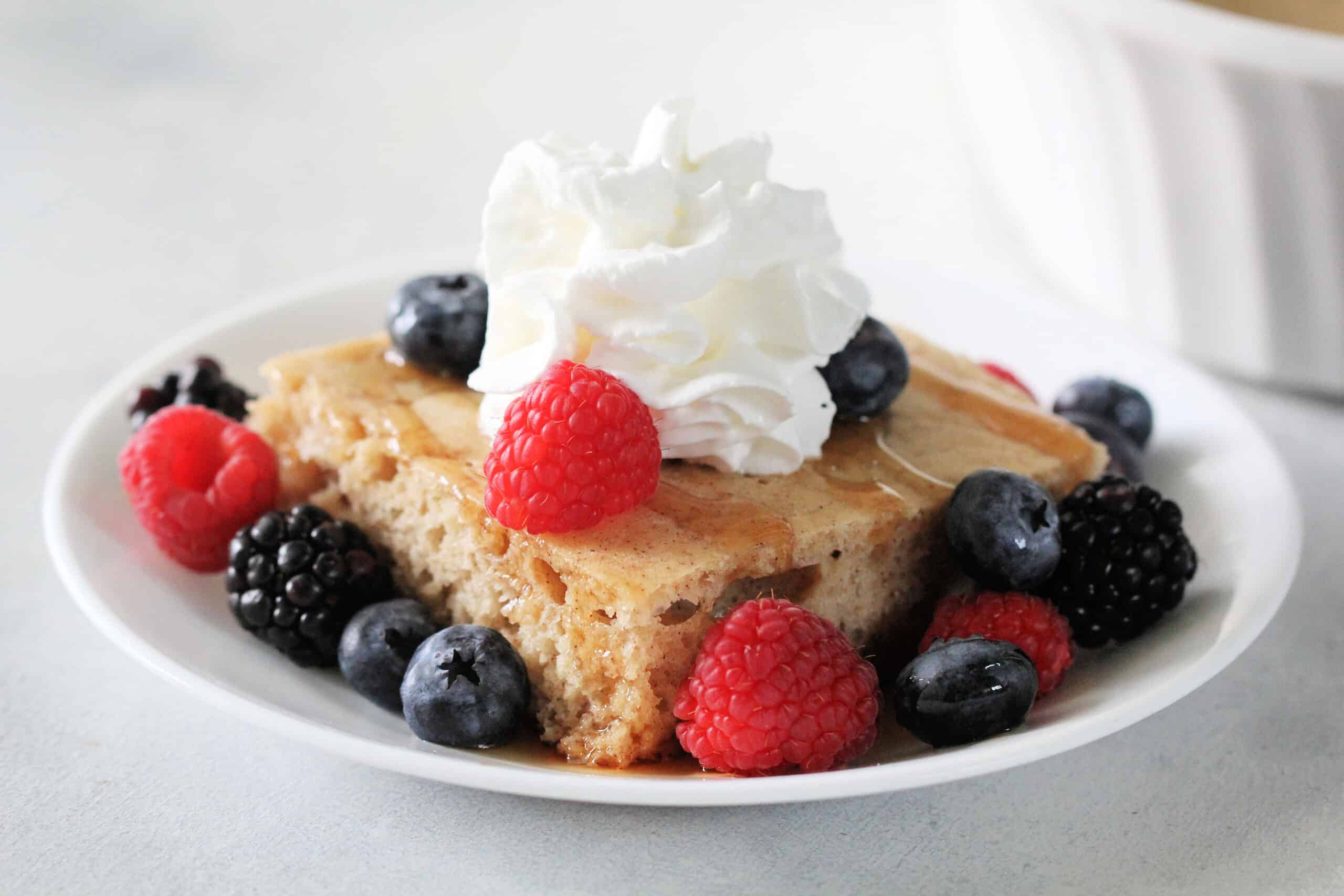 Baked Pancake on white dish with berries and whip cream