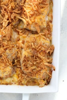 A close-up of a baked casserole dish filled with golden brown, crispy fried onions on top of melted cheese.