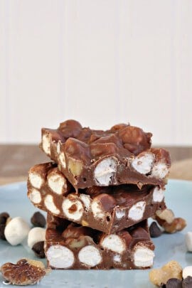 A stack of rocky road chocolate squares with visible marshmallows and nuts, placed on a light blue plate.
