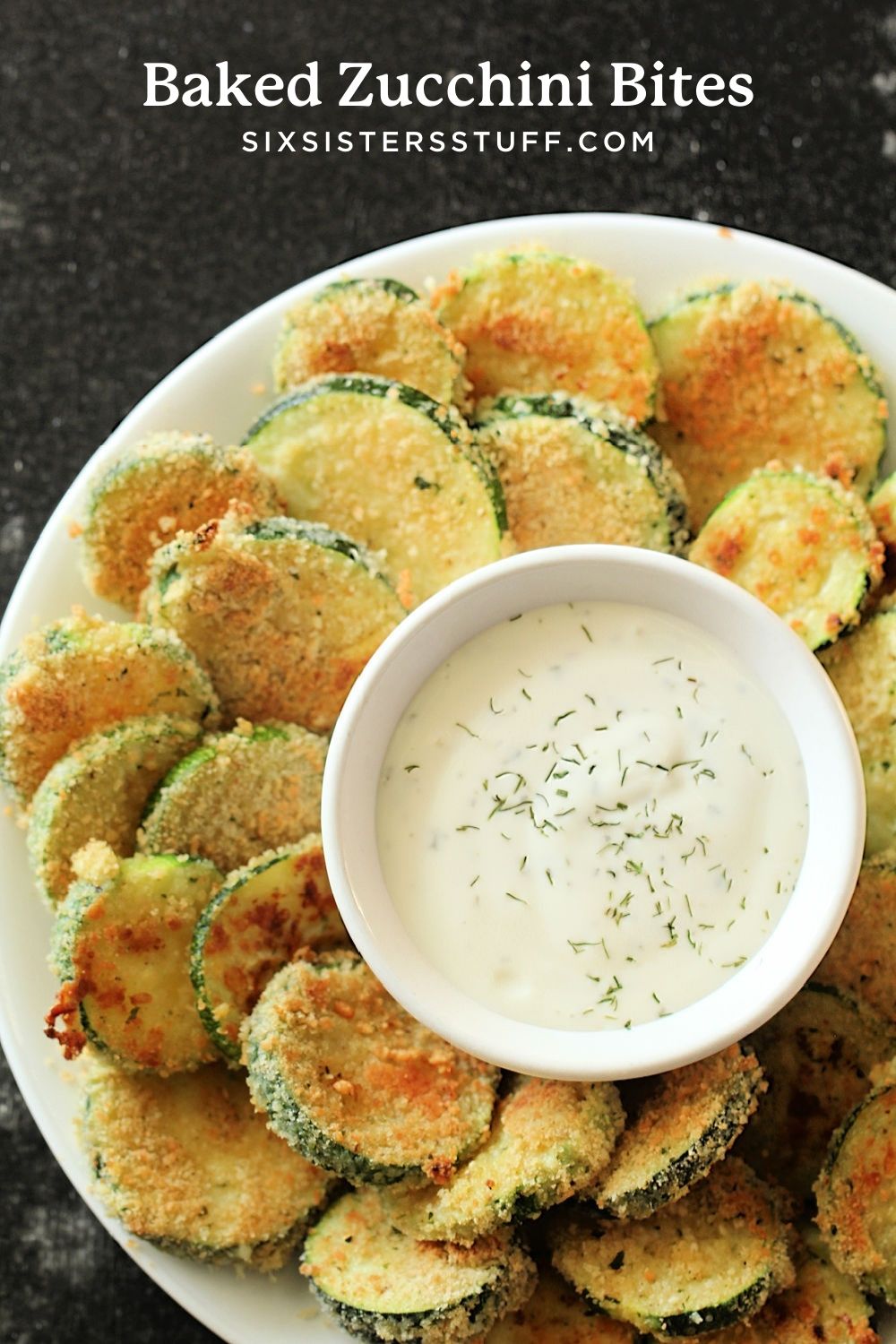 baked zucchini bites on a plate with a bowl of ranch dressing in the middle