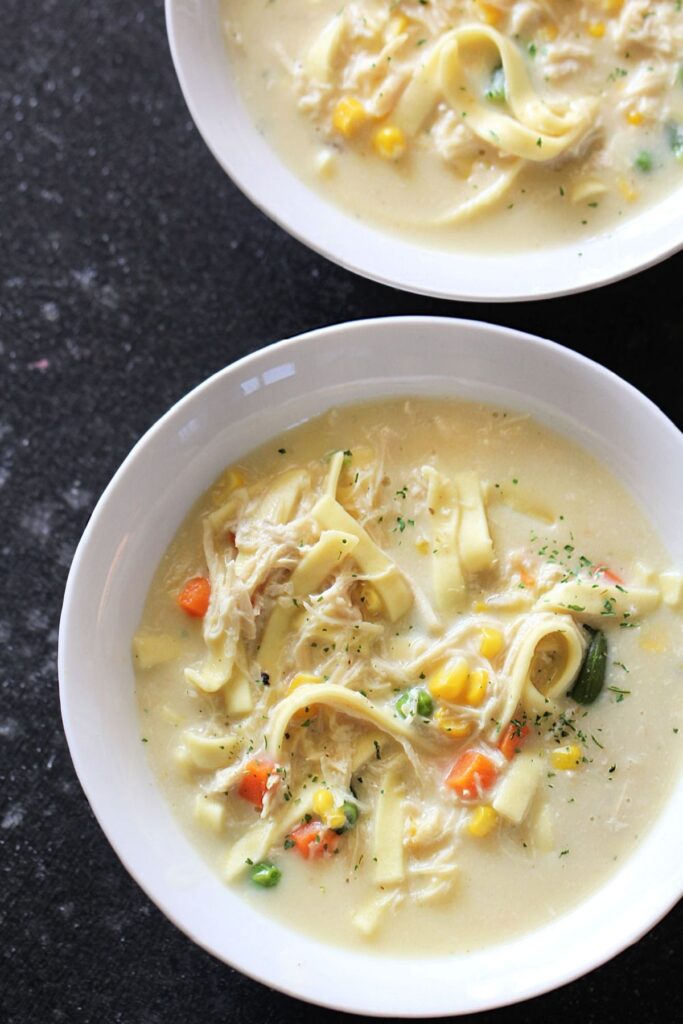 slow cooker creamy chicken noodle soup in a white serving bowl