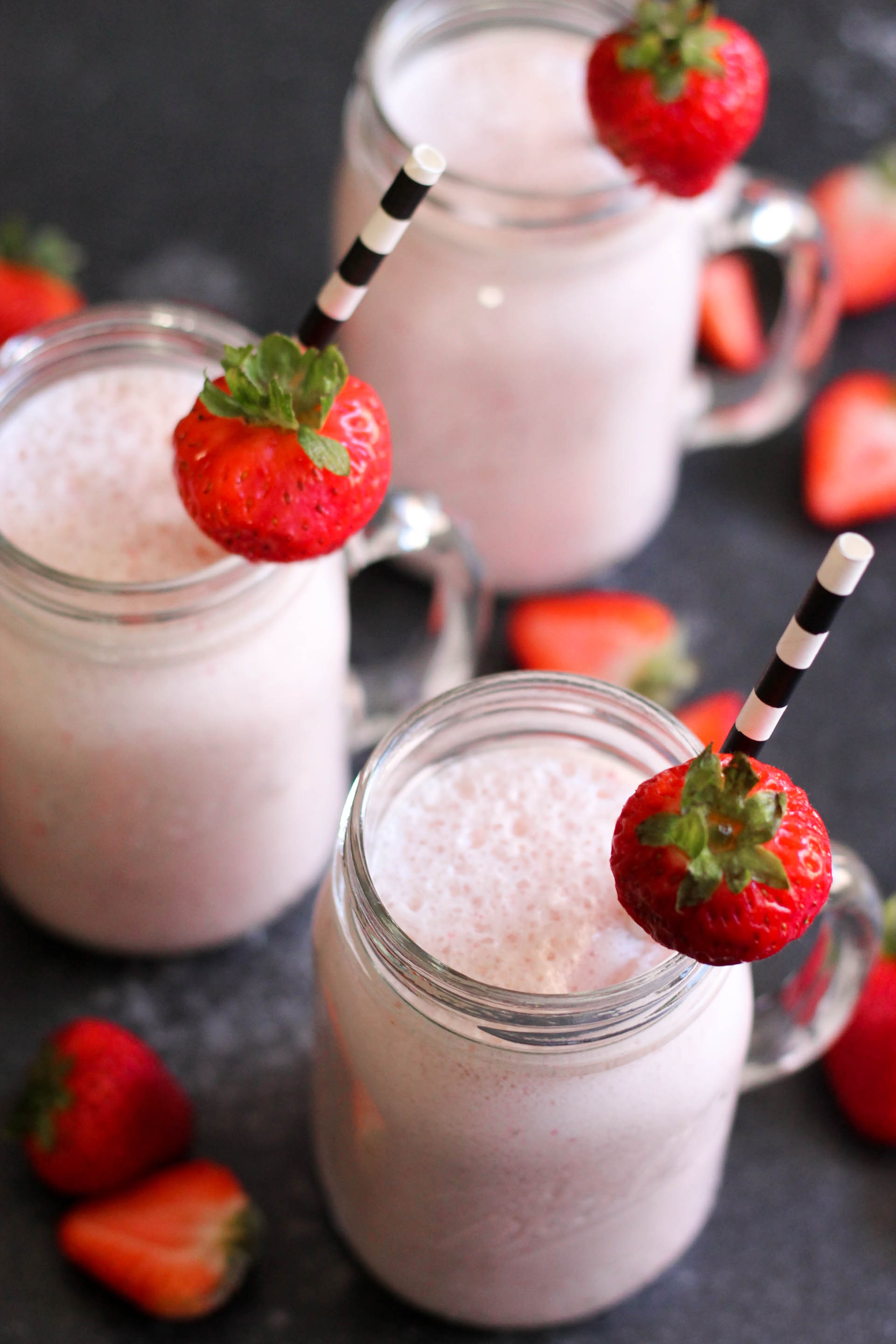 3 Homemade Strawberry Milkshakes in jars with straws and strawberries