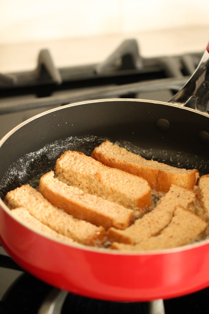 Skillet with uncooked Homemade French Toast Sticks cooking