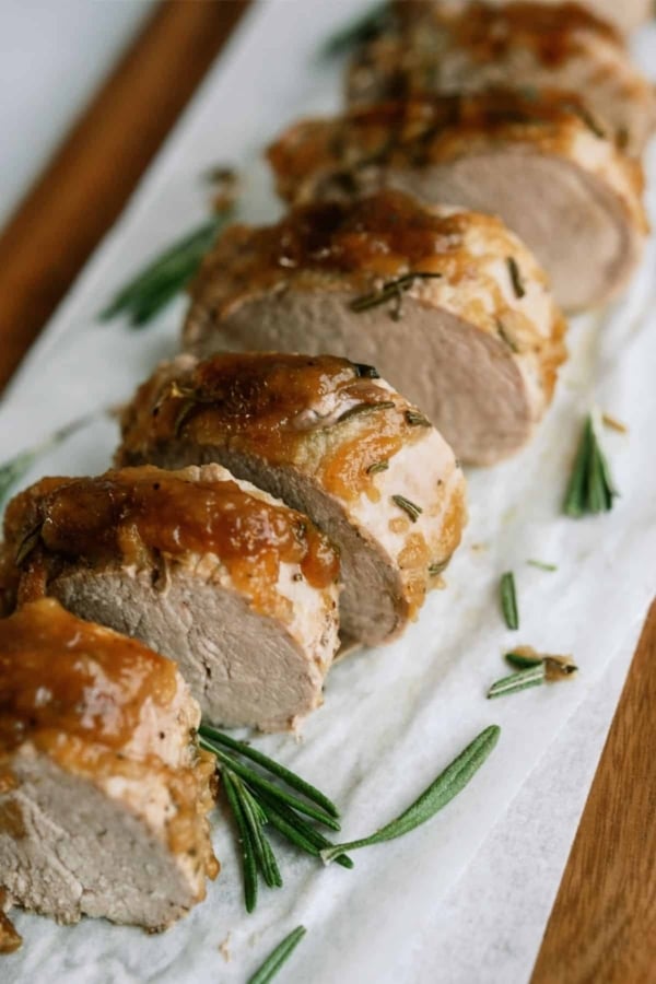 Slices of Pork Tenderloin on a serving tray lined with parchment paper.