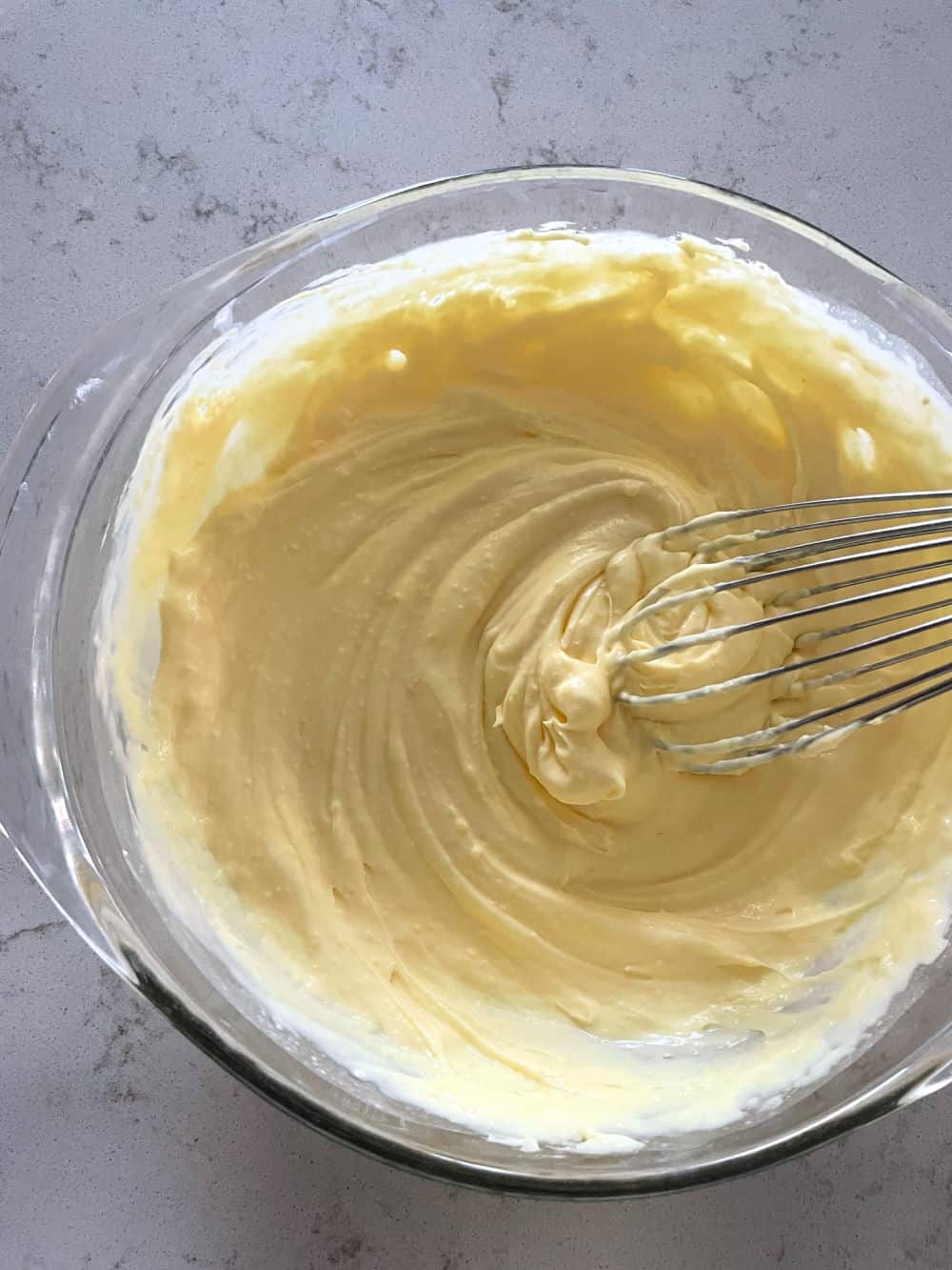 Homemade whip cream in a glass bowl with a whisk