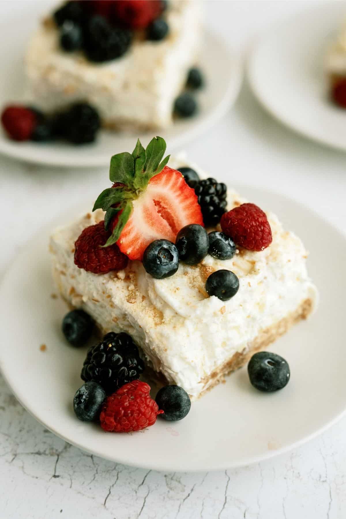 A slice of Fluffy Cream Cheese Dessert on a plate topped with fresh berries.