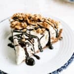 A slice of Chocolate Chip Cookie Ice Cream Pie on a plate drizzled with chocolate sauce.