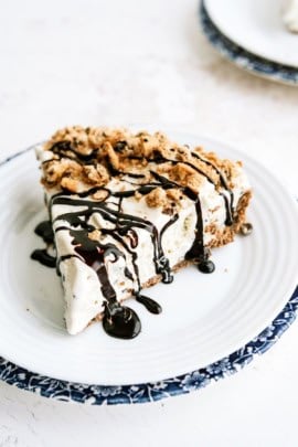 A slice of Chocolate Chip Cookie Ice Cream Pie on a plate drizzled with chocolate sauce.