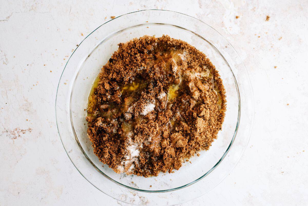 Cookie crumbs, sugar and butter in glass mixing bowl.