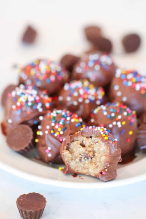 A plate of Reese’s Nutter Butter Cookie Truffles with one cut in half to see the inside of the truffle.