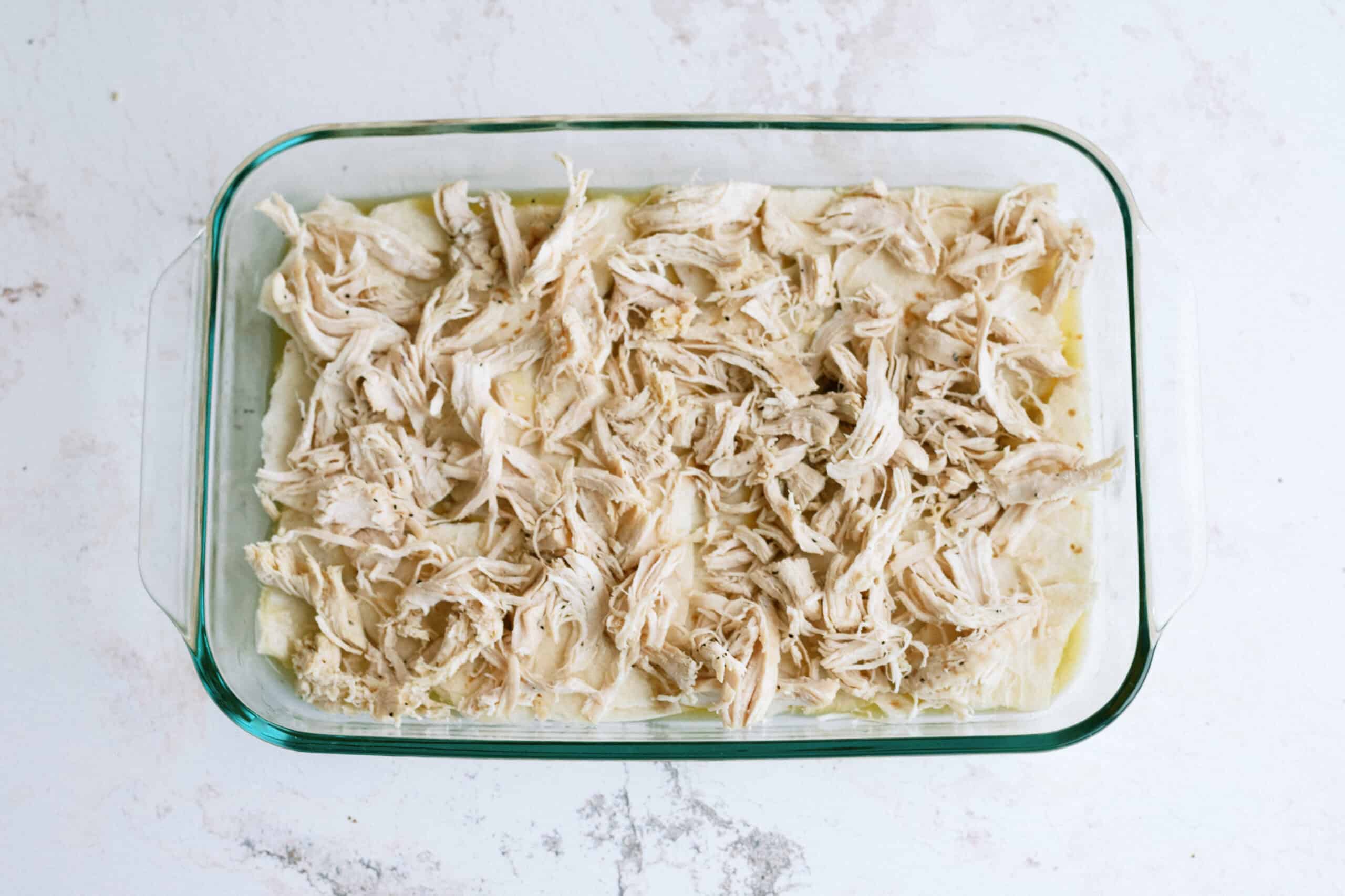 layers of green enchilada sauce, tortillas, and shredded chicken