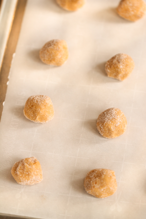 Cookie dough balls on a baking sheet lined with parchment paper