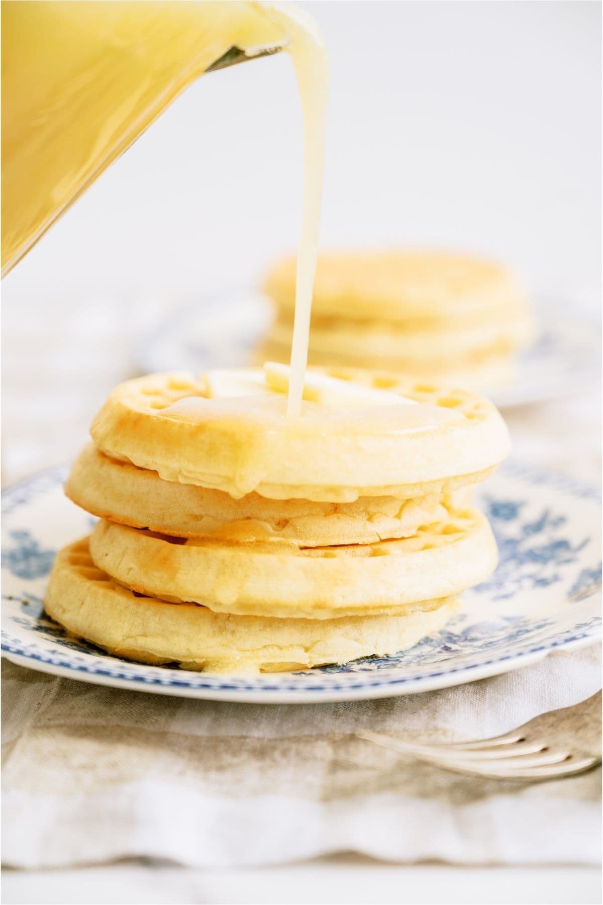 A stack of waffles with Buttermilk Syrup being poured on top.