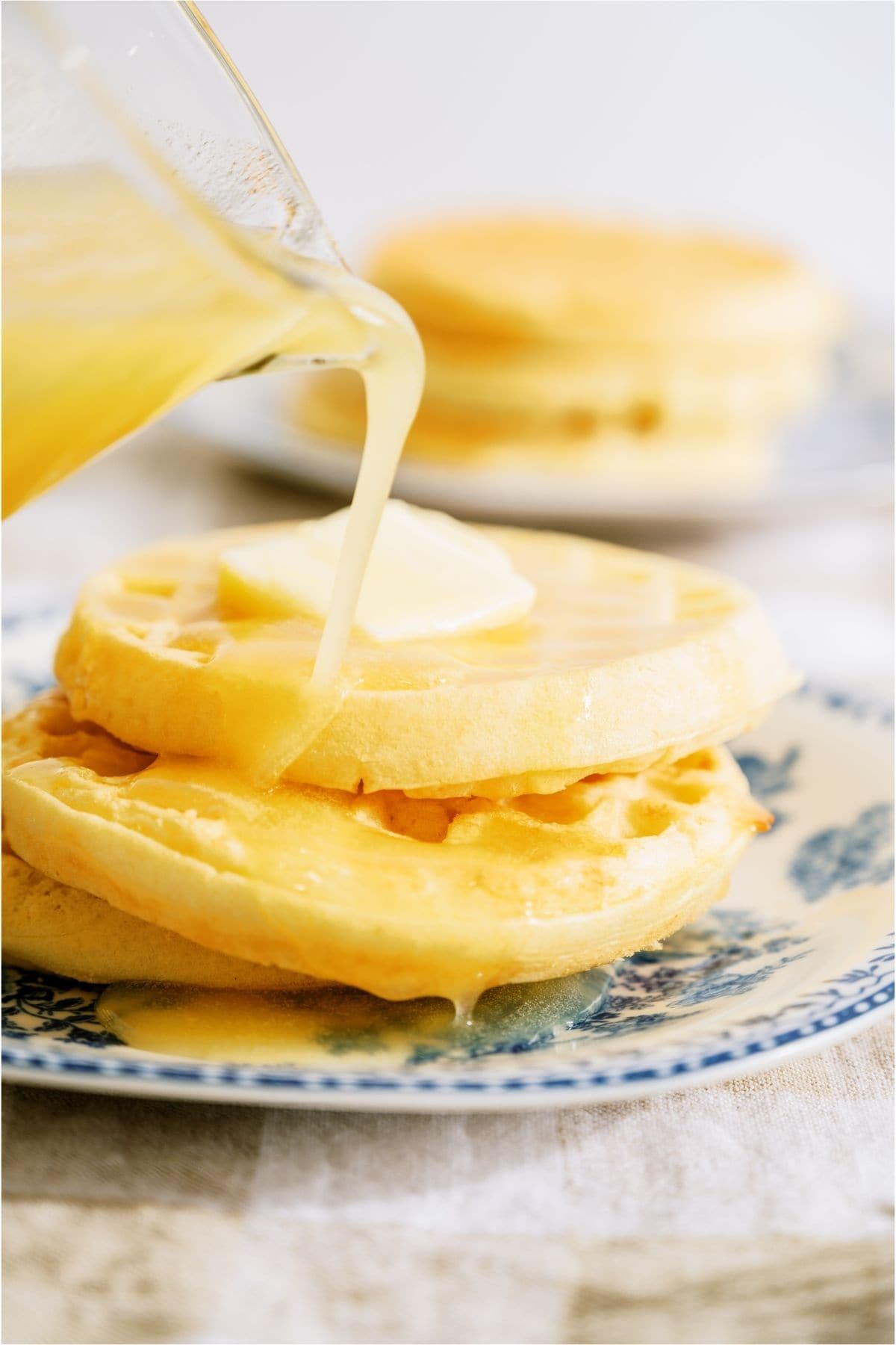 Buttermilk Syrup being poured on top of waffles on a plate.