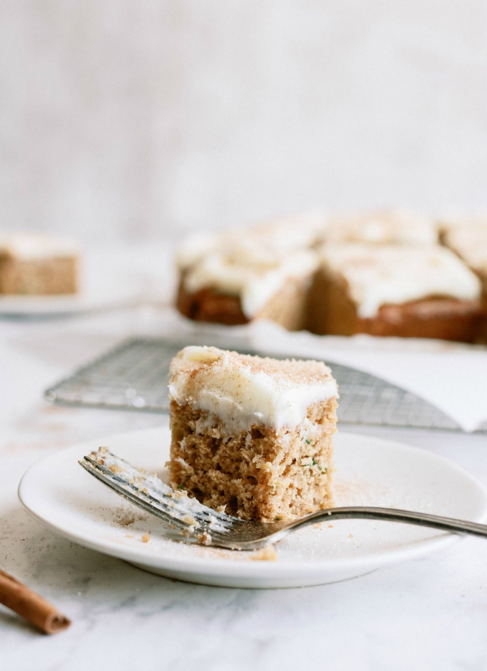 Slice of Cinnamon Zucchini Cake with Cream Cheese Frosting on a plate with fork
