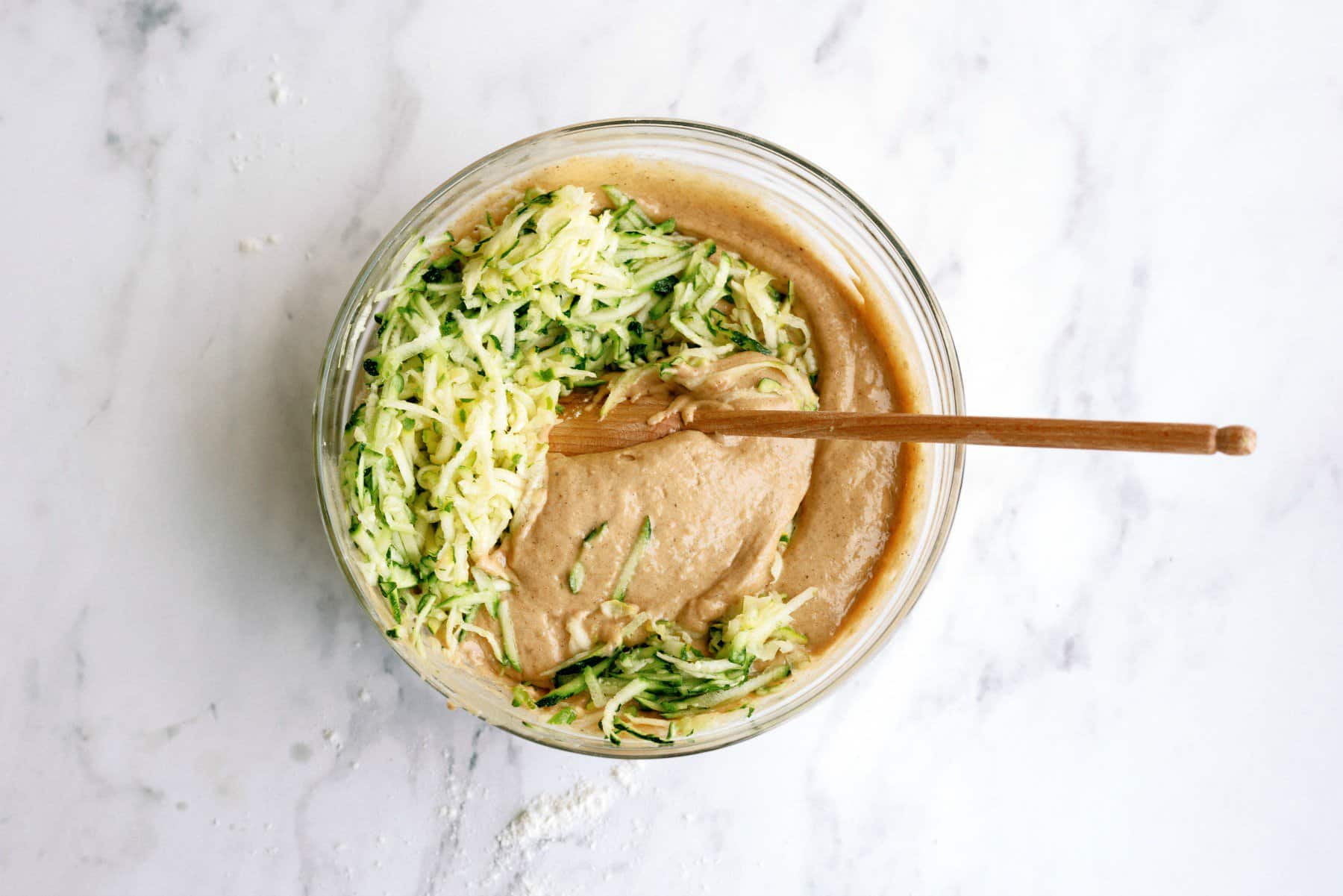 Cinnamon Zucchini Cake batter in a bowl with shredded zucchini