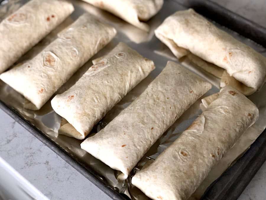 Unbaked Sweet Pork Chimichangas on a baking sheet
