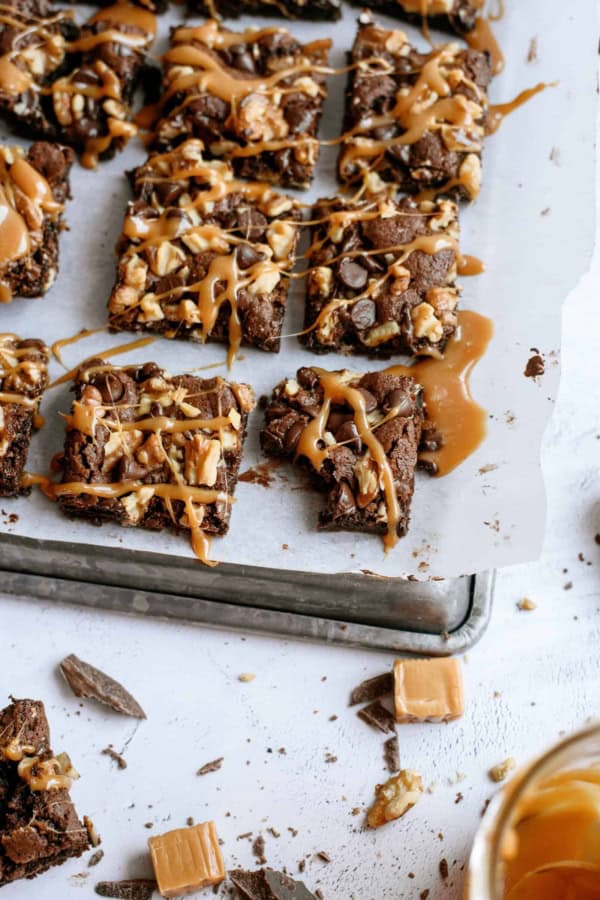 Chocolate Turtle Brownies cut into squares and on top of a parchment lined baking sheet.