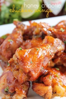 A close-up of honey chipotle chicken wings garnished with herbs, served on a white plate.