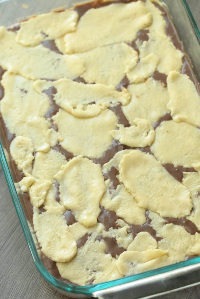 Cake Mix Cookie Bar dough on top of chocolate layer in baking dish.