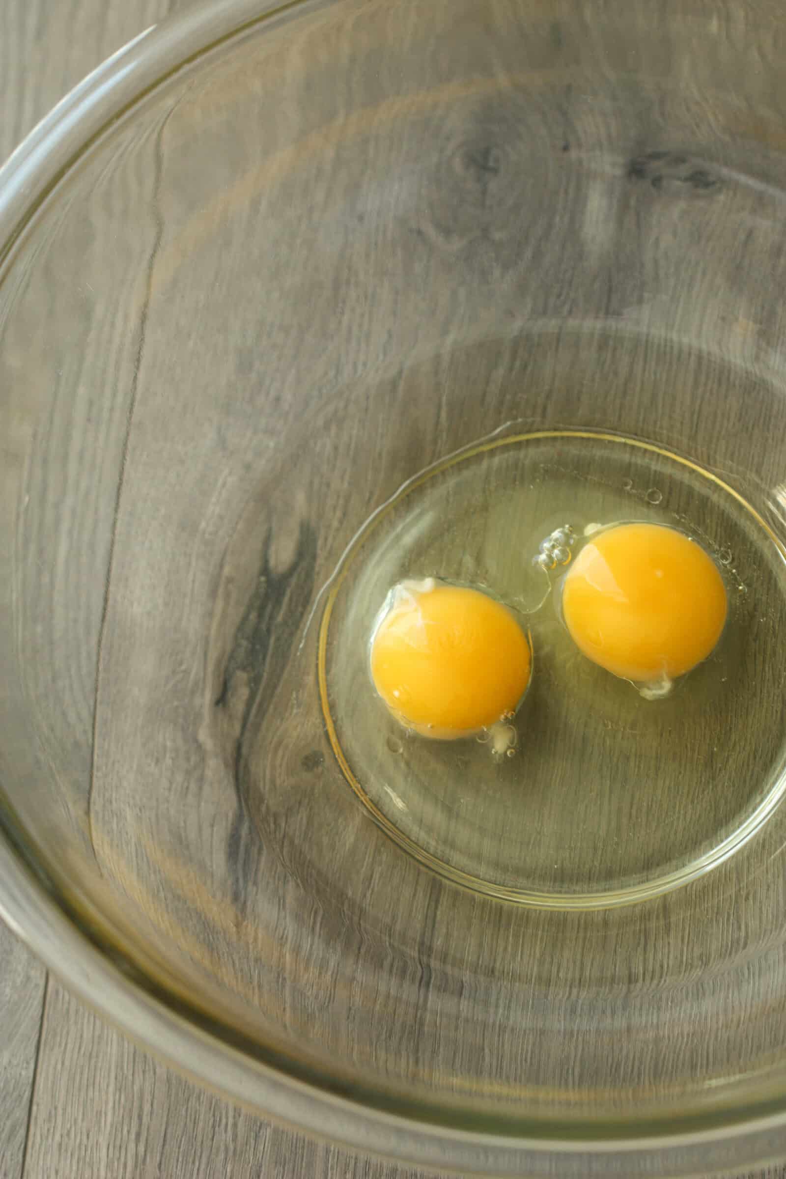 Two eggs in a glass mixing bowl